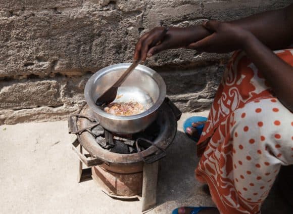A woman in Tanzania cooks a meal for her household using charcoal.