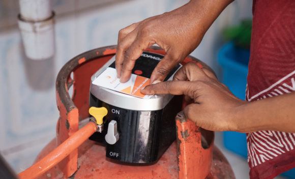 A KopaGas sales agent helps a customer with her Liquified Petroleum Gas (LPG) canister.