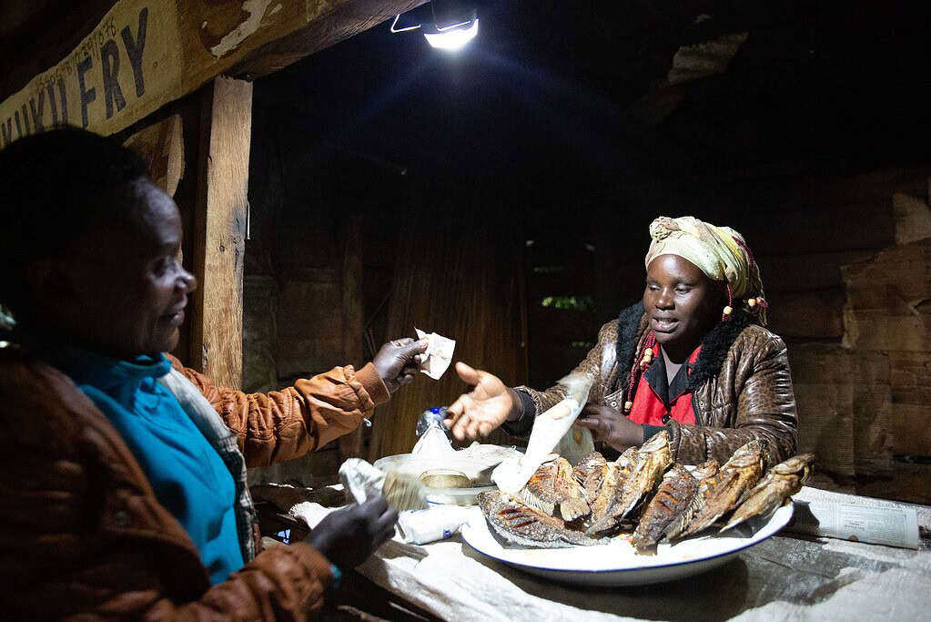 Vendor sells fried fish at a nighttime stand