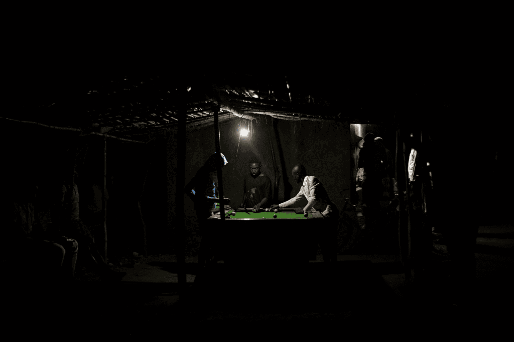 Men play pool with one overhead light