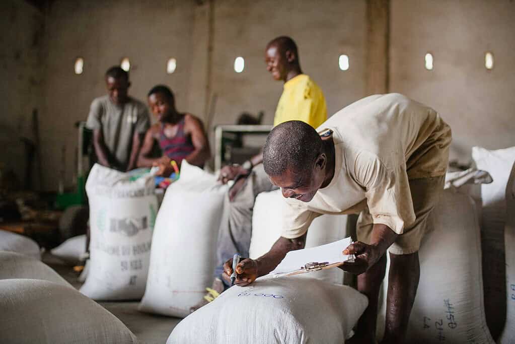Worker marks sack in a busy West African packing facility