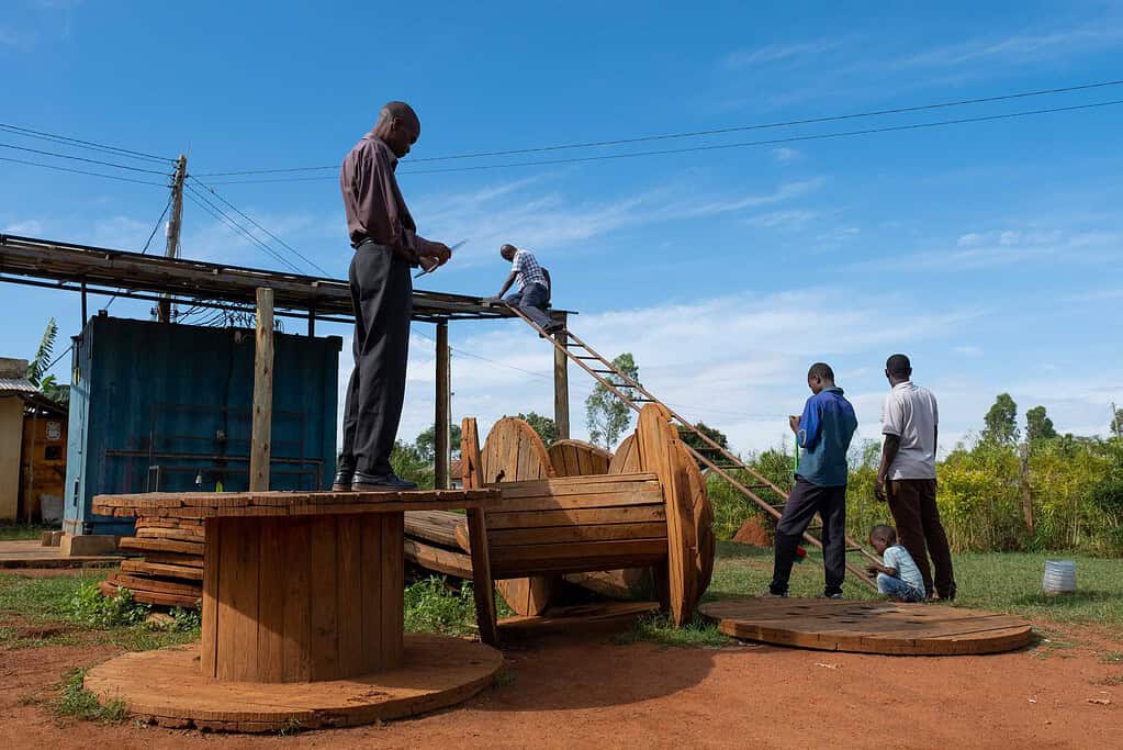Group of men planning the installation of solar planels on a shed while a child plays