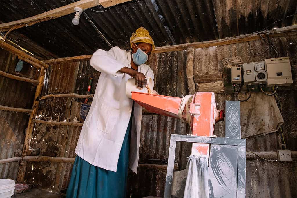 An African woman operates a maize milling machine.