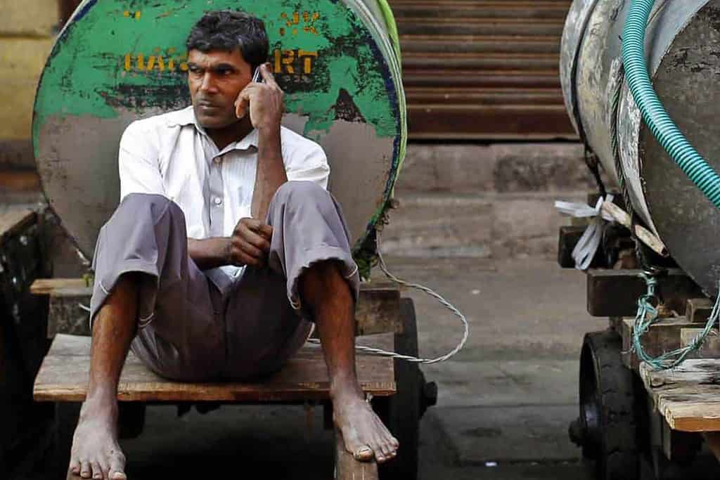 An Indian man seated and on the phone.