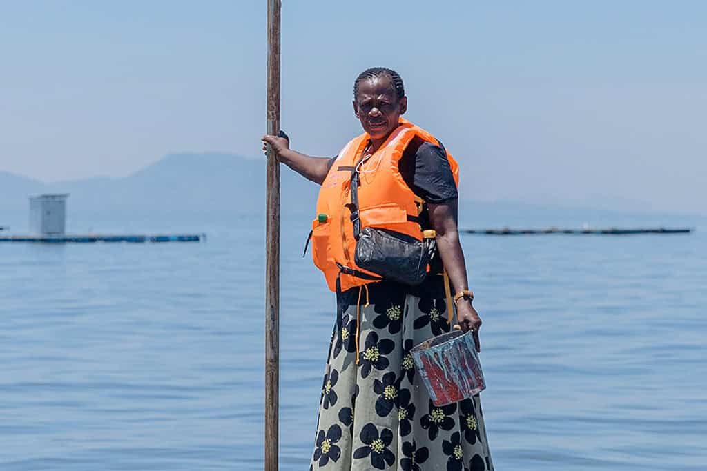 Woman feeds fish on lakefront fishing farm in Kenya