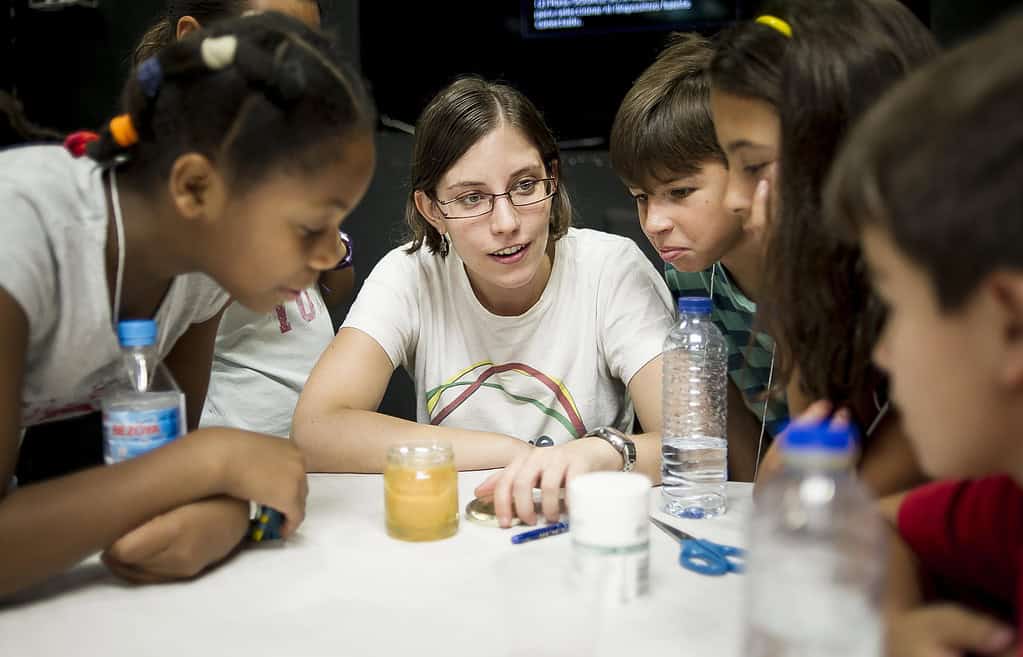 Acumen Fellow Cristina Balbas speaks with young children around a table in Spain
