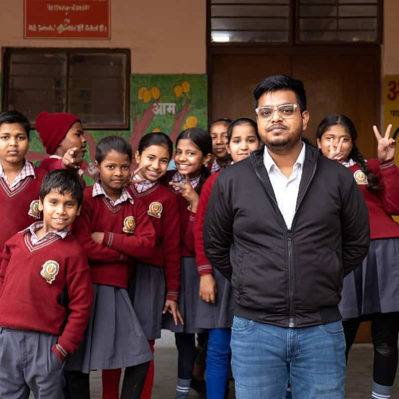 Teacher stands in front of students in Indian school yard