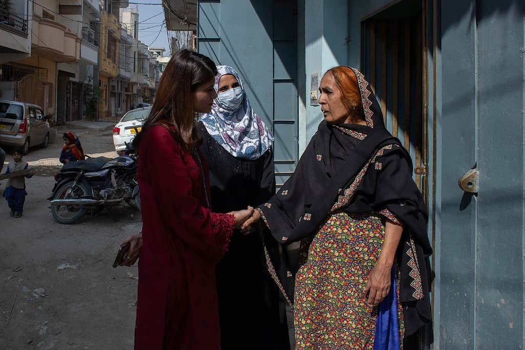 Women shake hands while conversing in the doorway of a Pakistani home
