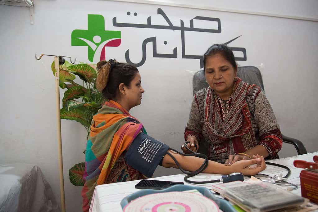 A clinician take the blood pressure of a female patient in a Pakistani clinic.