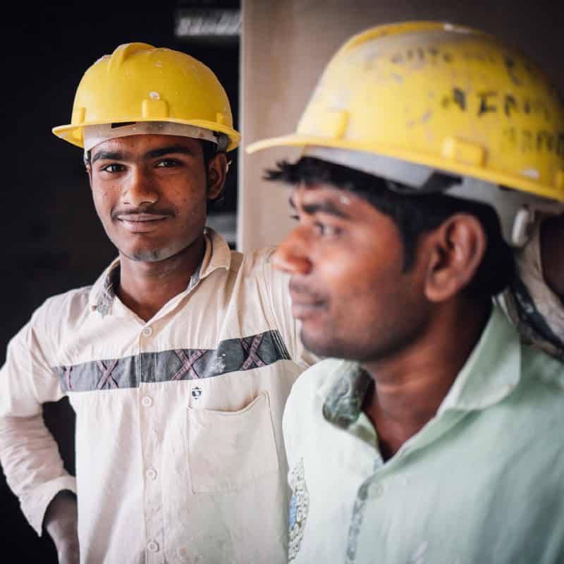 Two workers stand by a building pillar