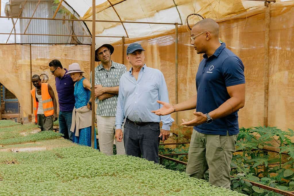 Worker tours group of investors through a greenhouse and farming operation