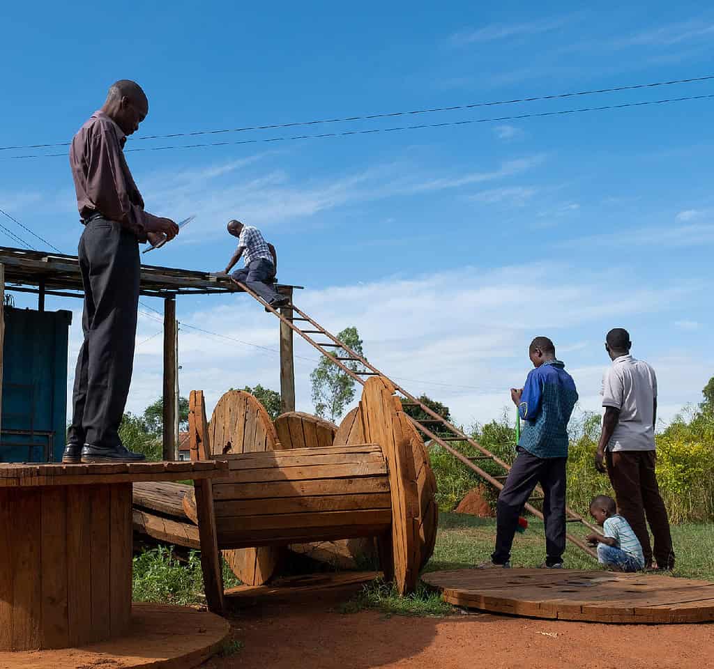Group of men planning the installation of solar planels on a shed while a child plays