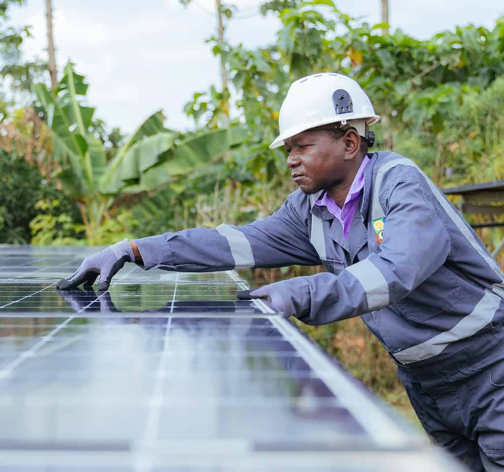 Technician inspects and cleans solar panel in East Africa field