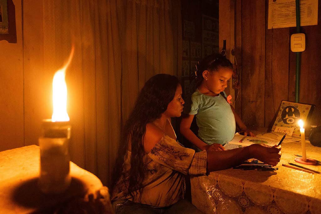 Mother helps child with her work assignment in rural Colombian candle lit home
