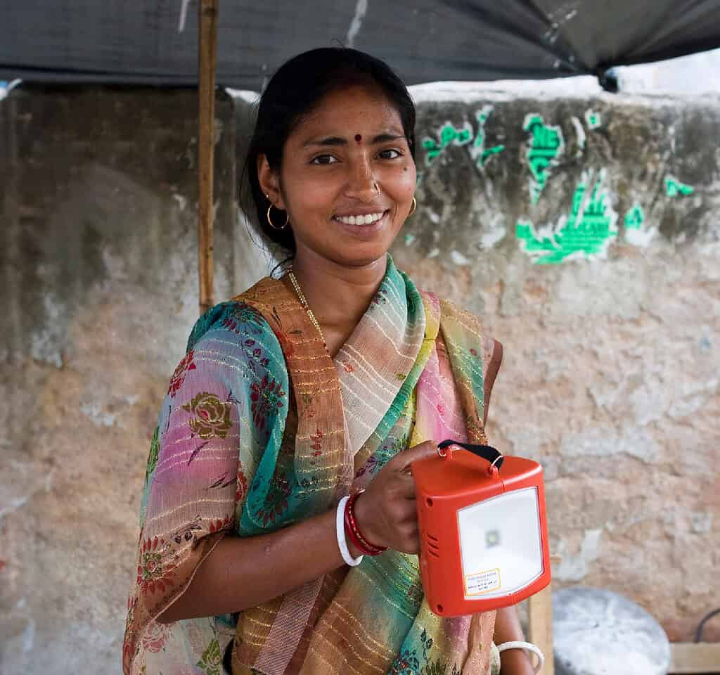 Woman smiles as she holds her solar powered lamp