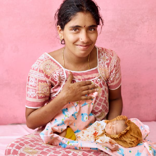 Women holding a newborn child in her home in India