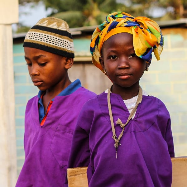 2 children standing outside of a school in Sierra Leone