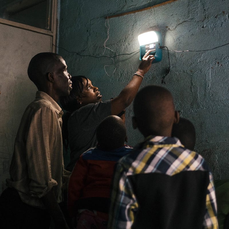Technician shows family how to operate solar powered lighting in East African home