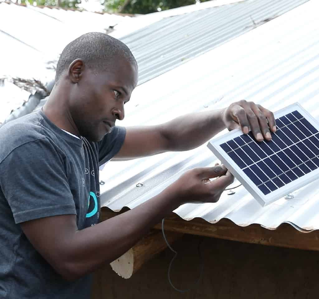 Man carefully installs solar panel on a roof