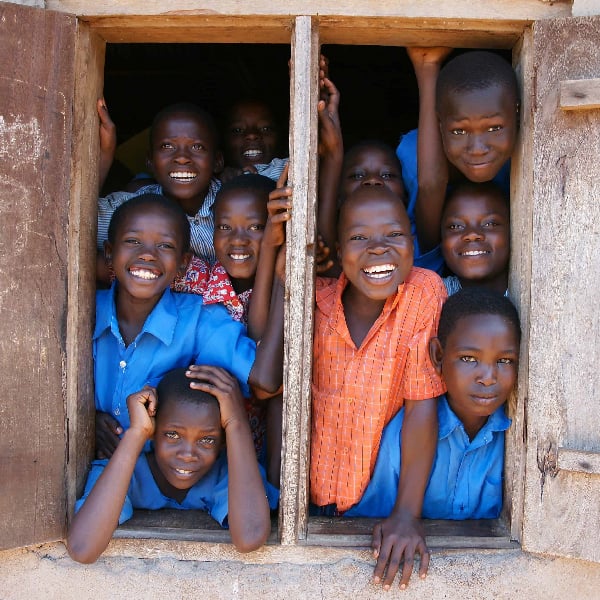 A group of school children gleefully lookout the window from a building in Kenya