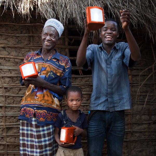 A happy and cheerful family holding solar powered lamps in front of their home