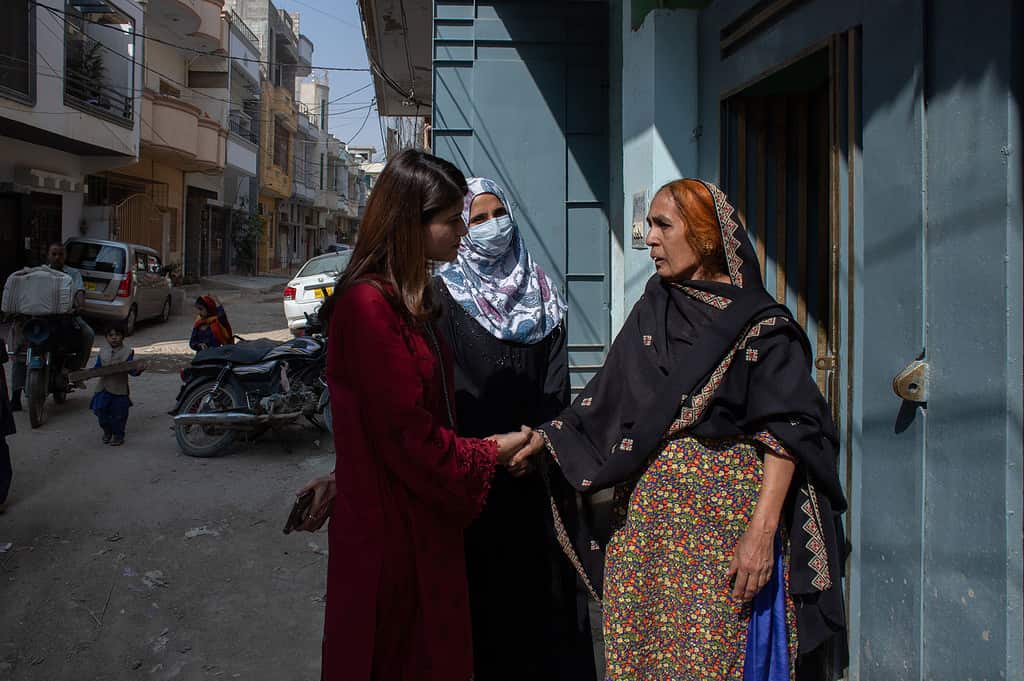 Women shake hands while conversing in the doorway of a Pakistani home