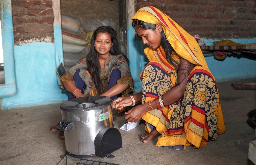 2 women in a home preparing to cook on a Greenway Grameen cookstove