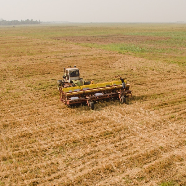 Tractor works a large farming field in preparing for seeding