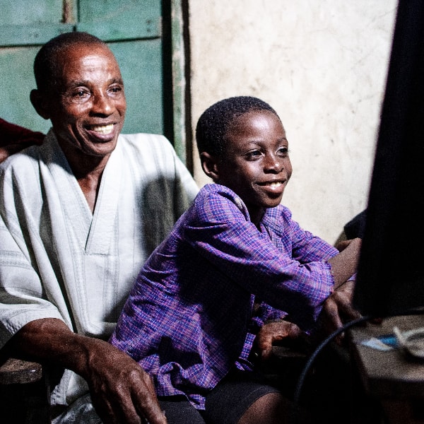 A child sat upon father's lap while both gleefully smile in their home