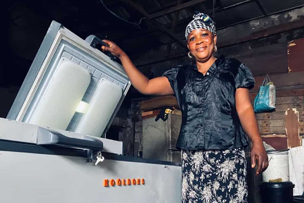 Woman opens her Koolboks refridgeration system within a shed