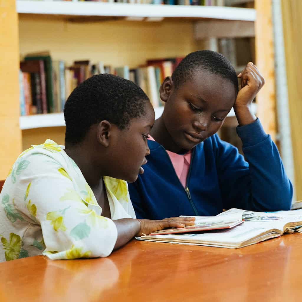 Two children read books at a library in East Africa