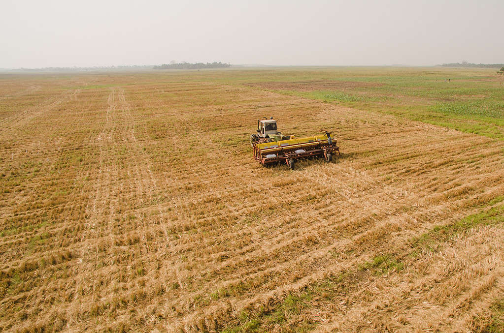 Tractor works large dry field for upcoming farming season in west Africa