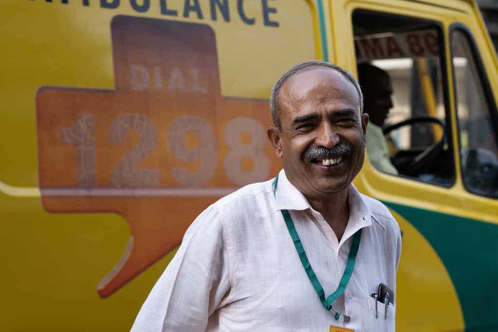Ambulette driver smiles outside of his Ziqitza ambulette before a dispatch in India