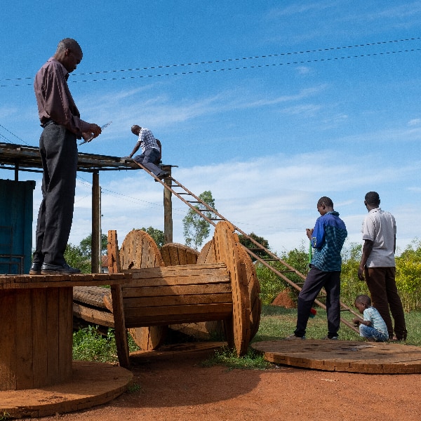 Group of men planning the installation of solar planels on a shed while a child plays
