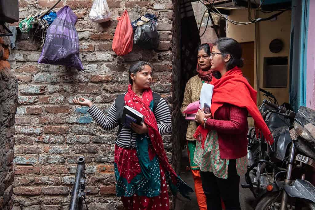 3 women have a discussion in a Indian neighborhood alleyway