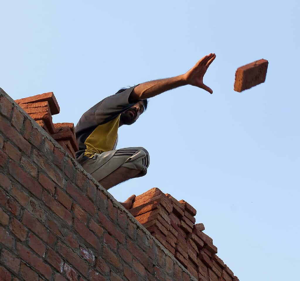 Man tosses extra brick from stack of bricks in Pakistan