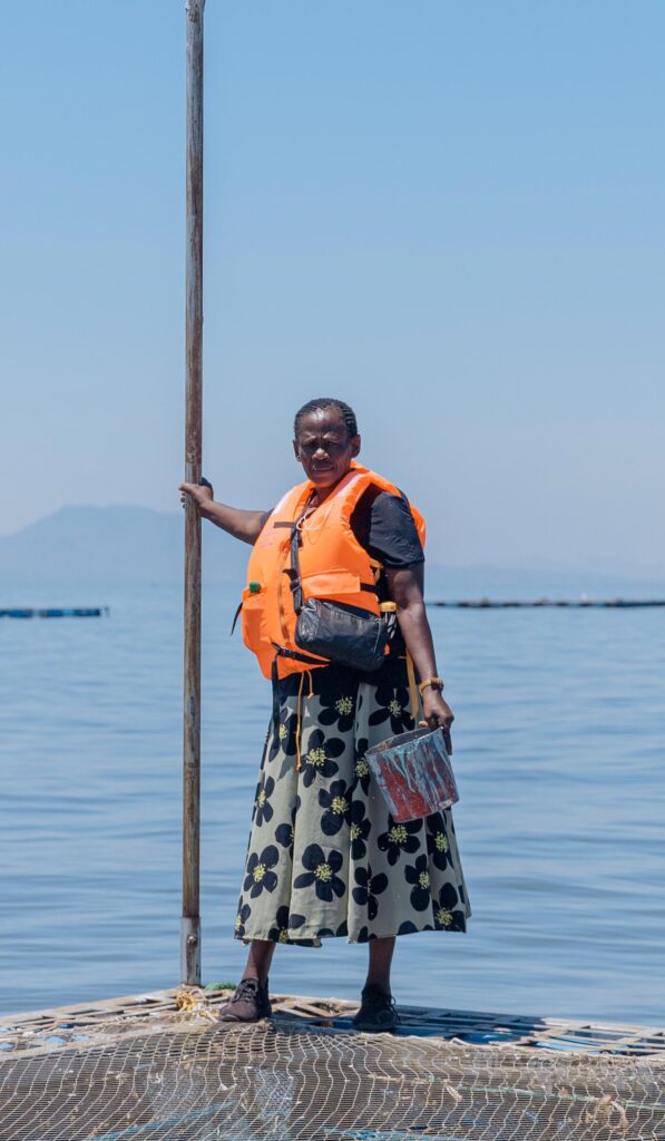 Women stands on lake side fish farm in Kenya