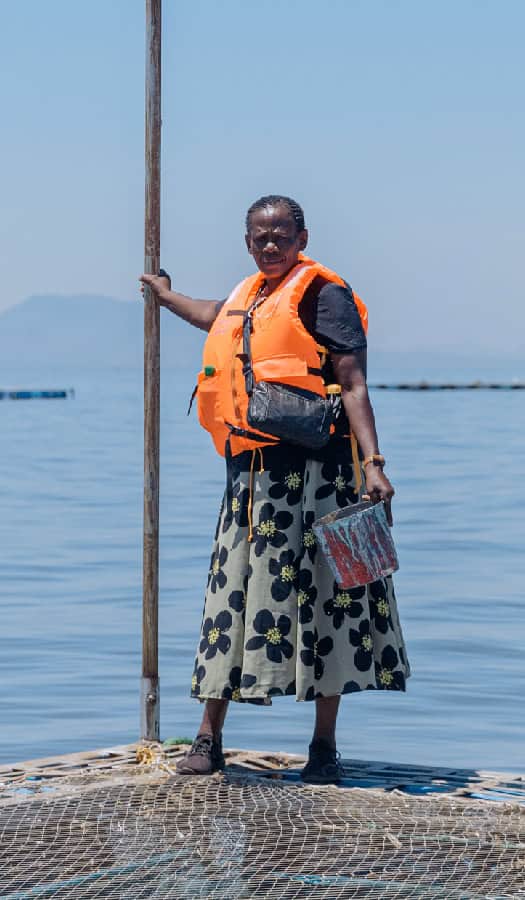 Women stands on lake side fish farm in Kenya