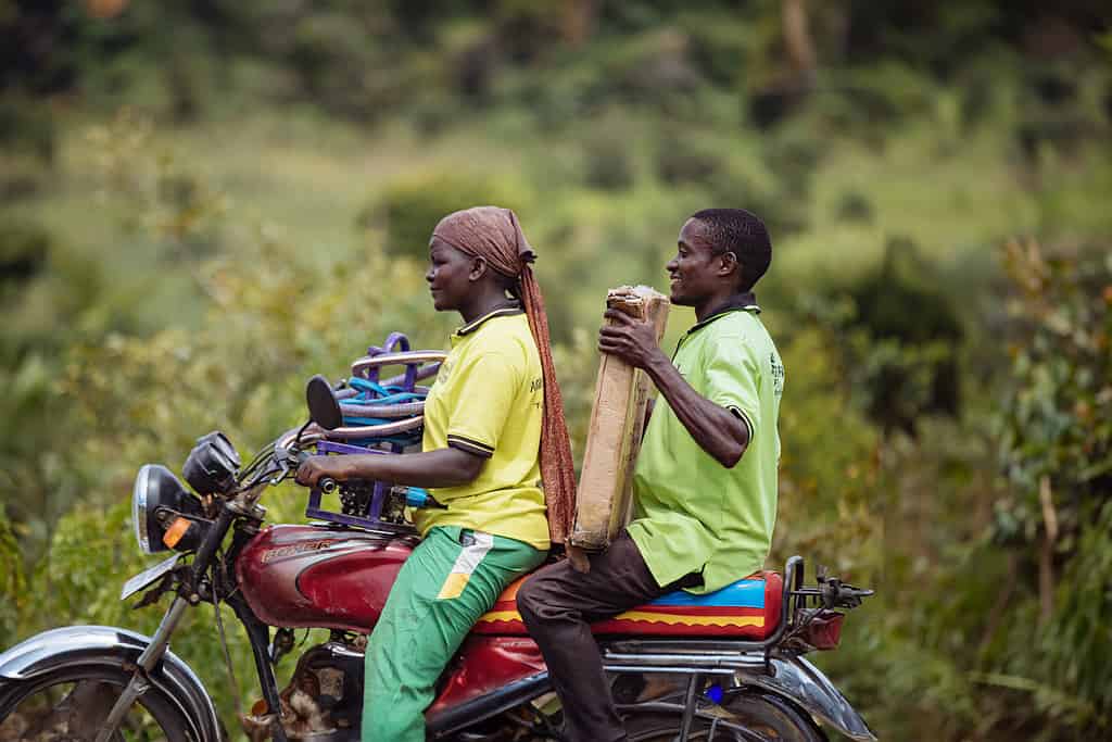 Man and women ride a motorcycle in East Africa while carrying solar panel equipment