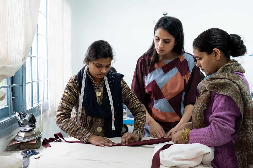 Acumen Fellow Gayatri Jolly shows women how to hem garment in a India teaching facility