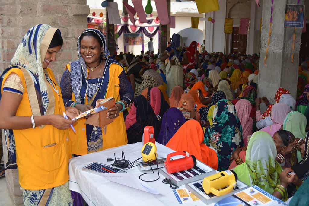 Solar lamp representatives smile cheerfully at large function in India