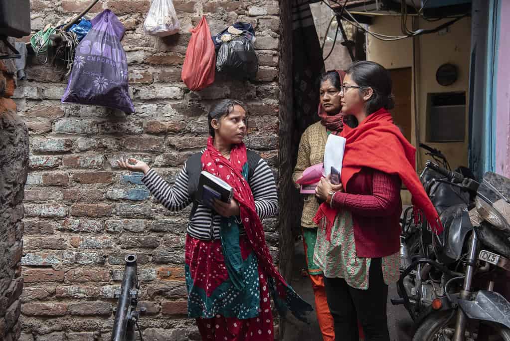 3 women have a discussion in a Indian neighborhood alleyway