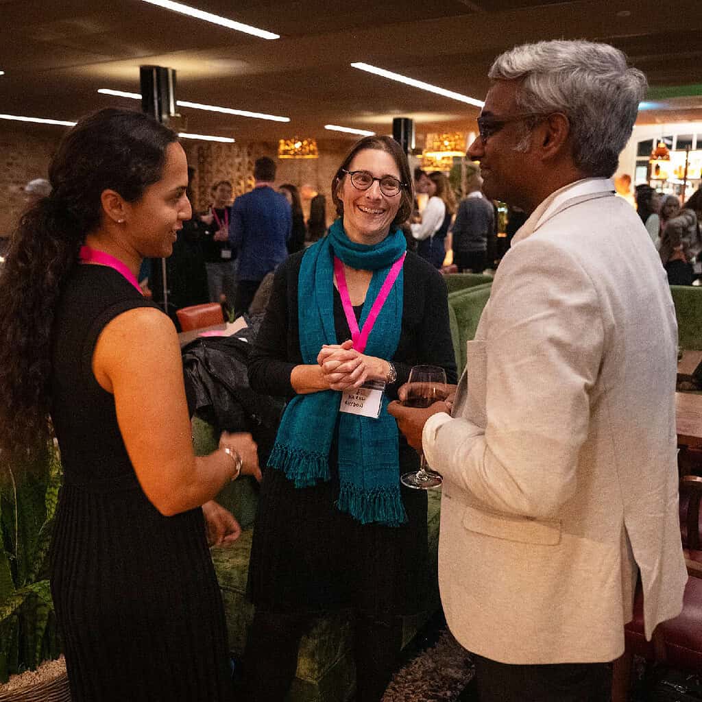 Group of Acumen Partners chat and socialize at Acumen event