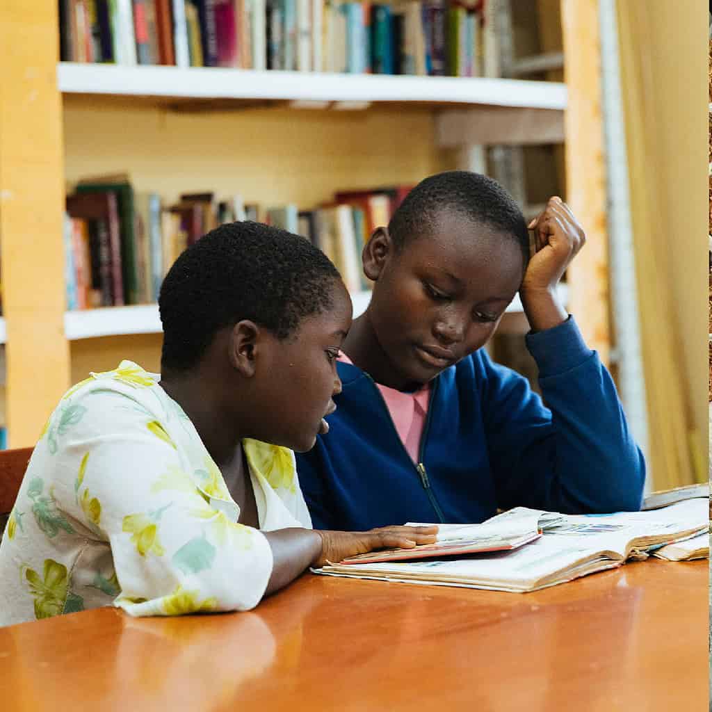 Two children read books at a library in East Africa