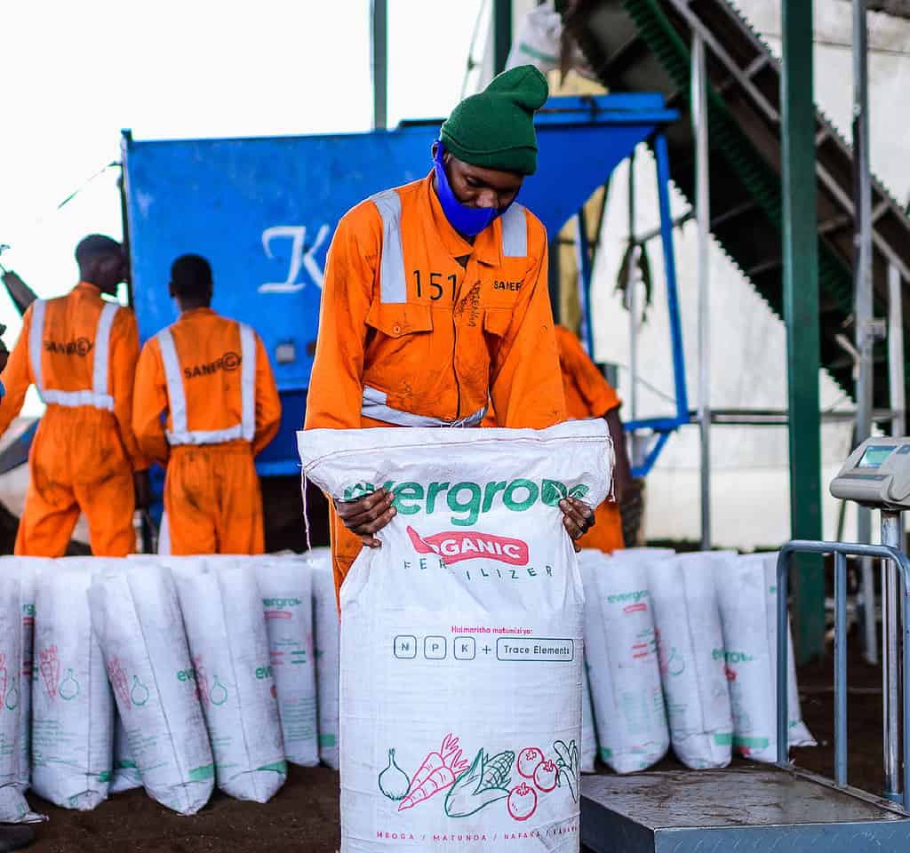 Worker seals bag of Fertilizer for shipping in busy East African processing facility