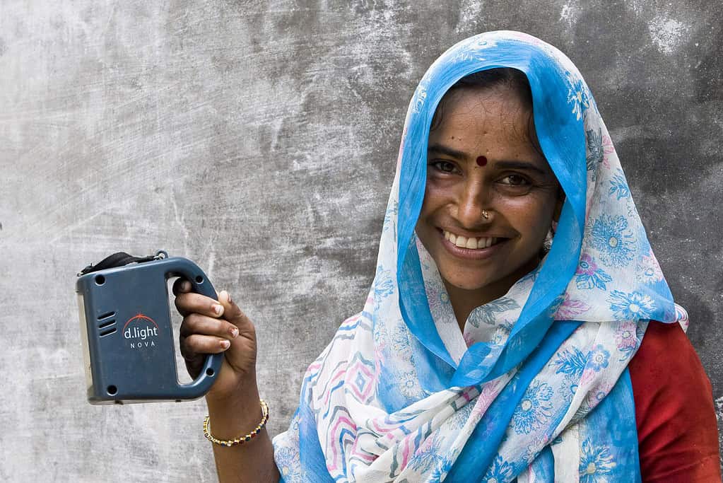 Woman cheerfully smiling while holding d.light solar powered lamp