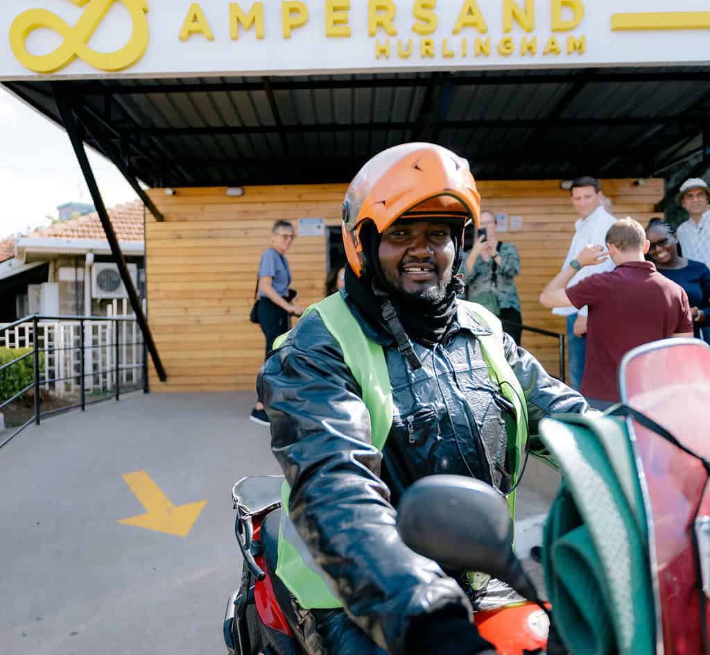 Man smiles while riding out his electric motorcycle from the Ampersand facility