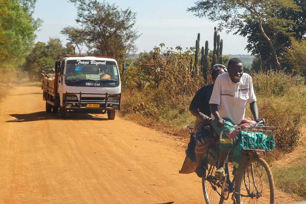 Man and women ride bike on Malawi road with cars