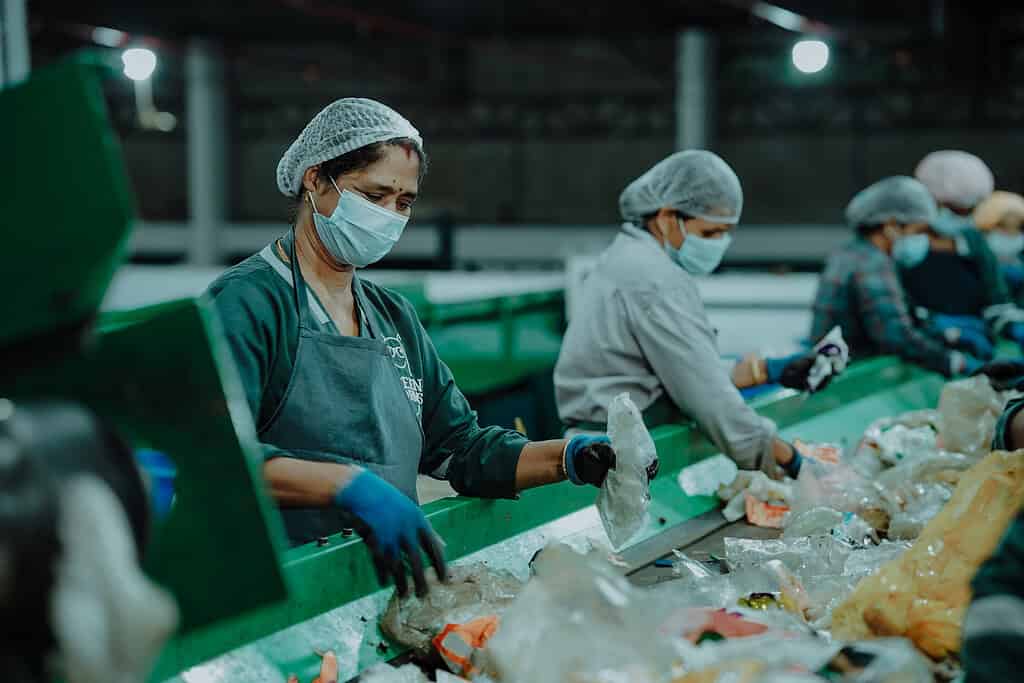 Workers in a sorting facility sift through recyclable materials