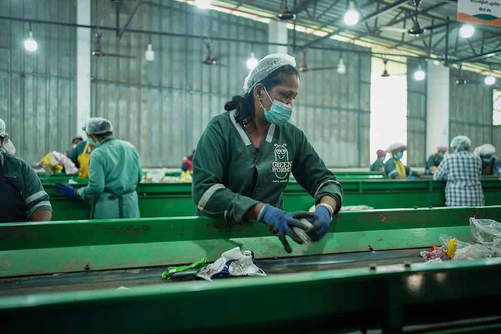 Worker sorts recyclable materials in Green Worms processing facility